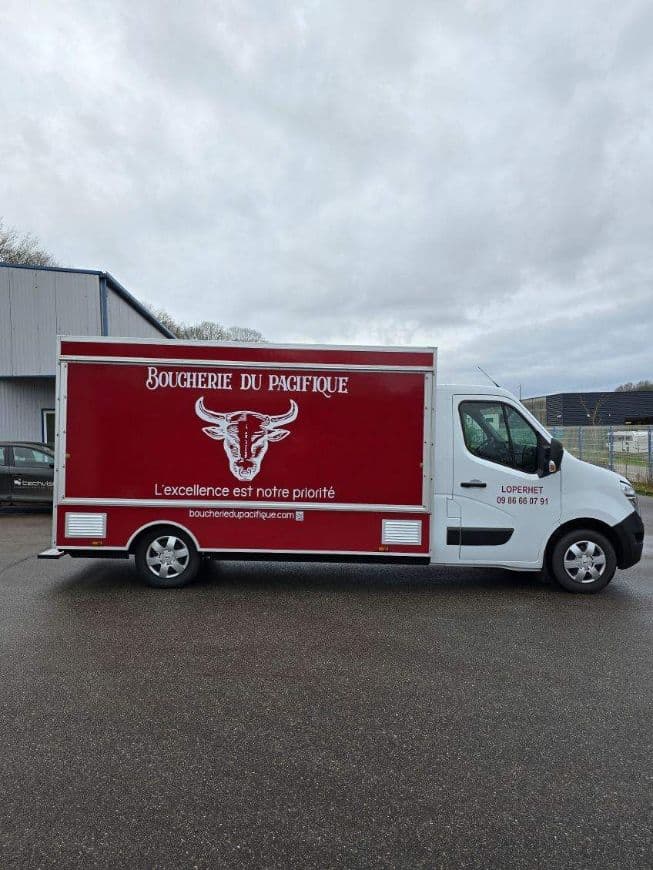 Le camion-boutique de la Boucherie du Pacifique vu de profil, habillage rouge enseigne et taureau blanc.